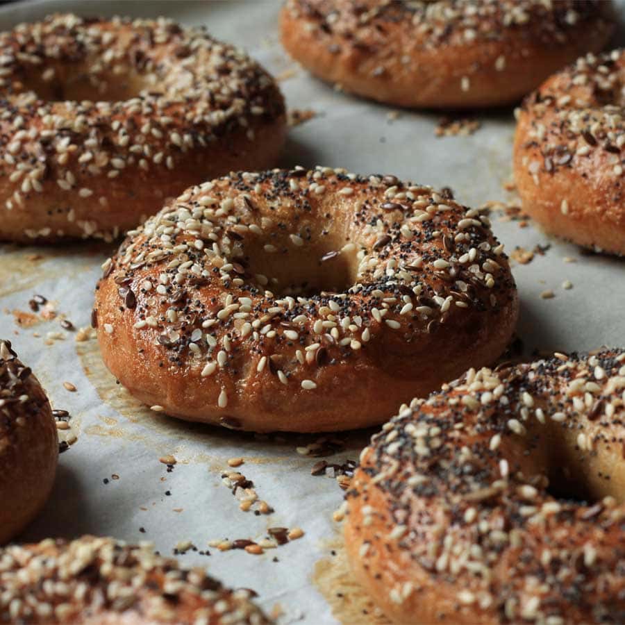 בייגל אפוי עם זרעי שומשום, פשתן, זעתר על מגש אפייה-מתכון לבייגל